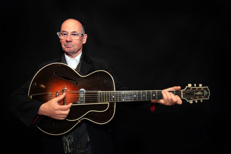 Musician Andy Fairweather Low holding a guitar