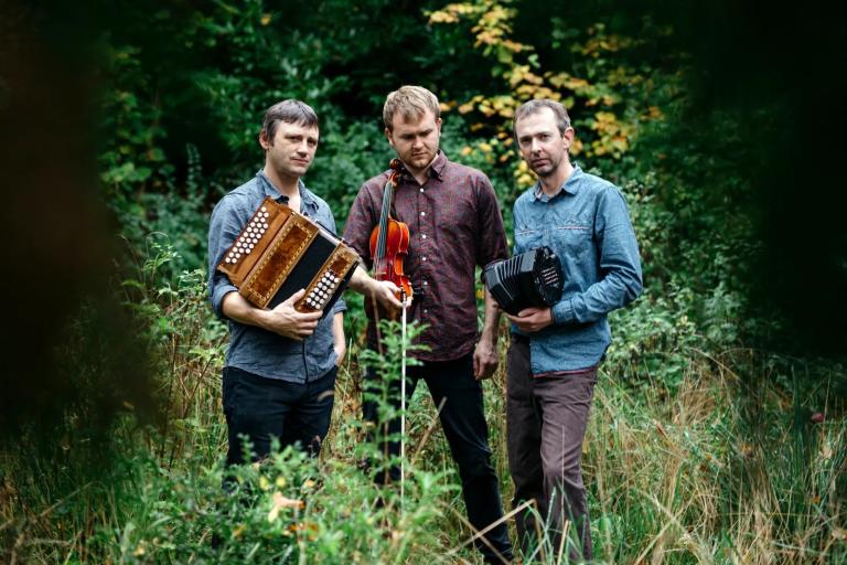 Three men holding instruments in a field