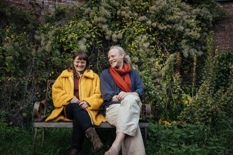 A woman in yellow anorak next to a man on a bench
