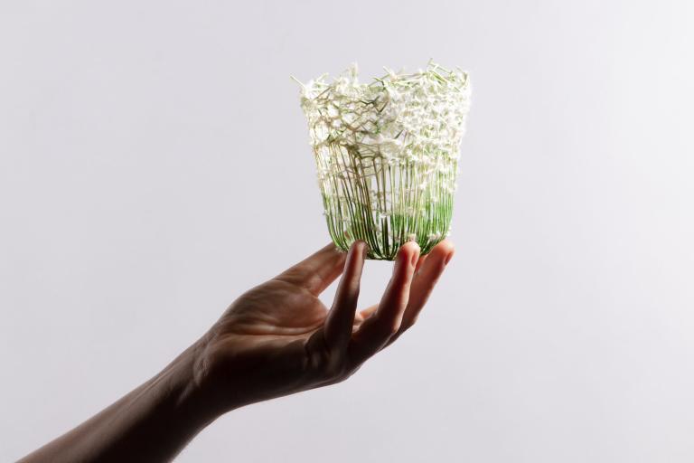 A hand holding a small vase