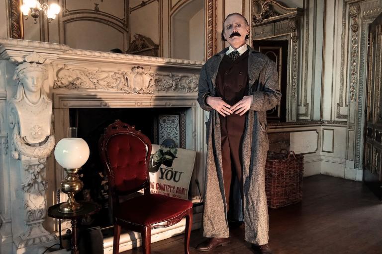 A man standing in front of a gothic fireplace