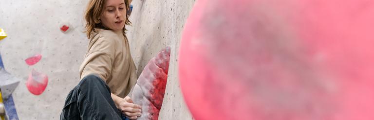 A woman scaling a climbing wall