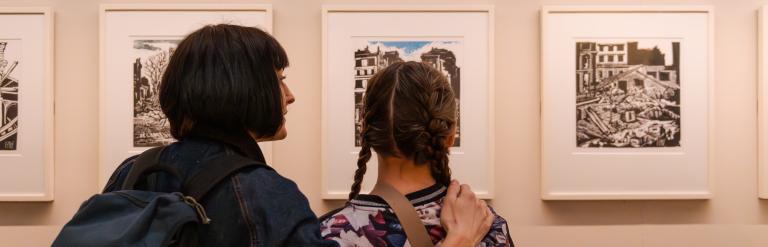 A woman and girl looking at works of art on a wall