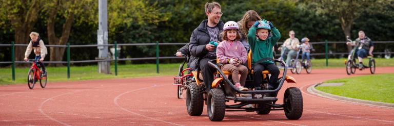 A family on a peddle bike on an athletics track