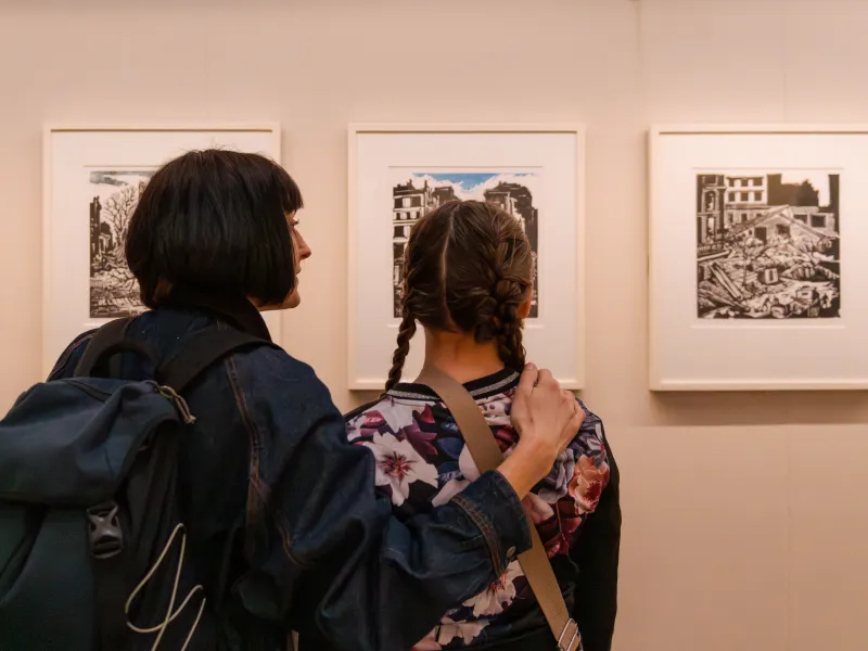 A woman and girl looking at works of art on a wall