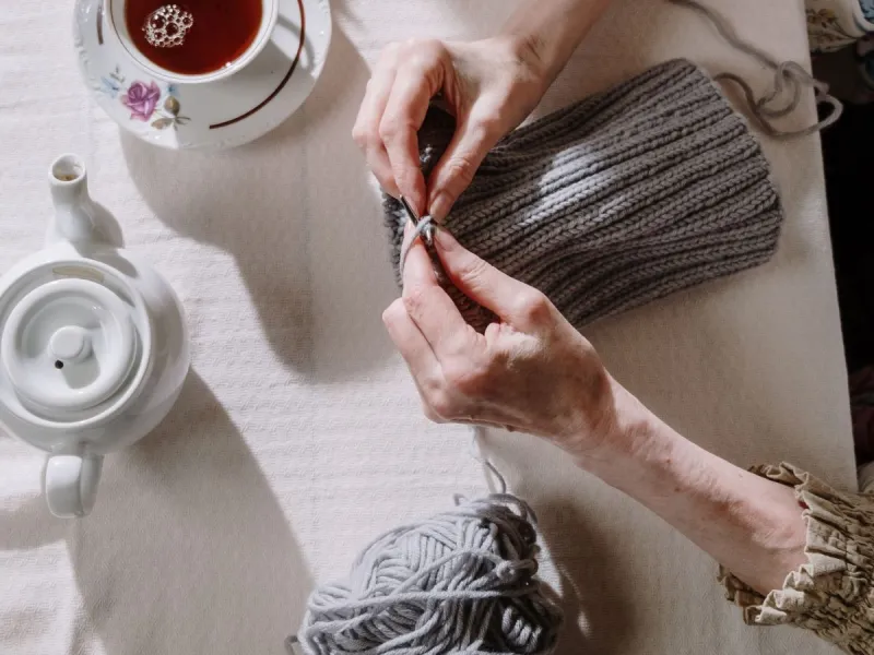 Pot of tea and hands knitting.