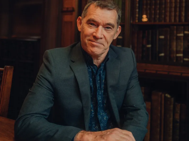 A photo of the storyteller Steve Taylor with bookshelves behind him