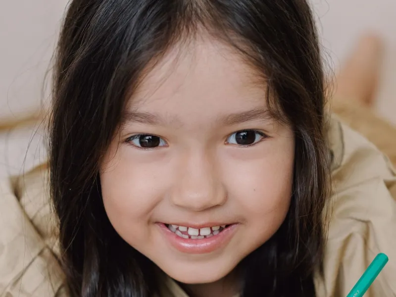 Young girl smiling and writing.