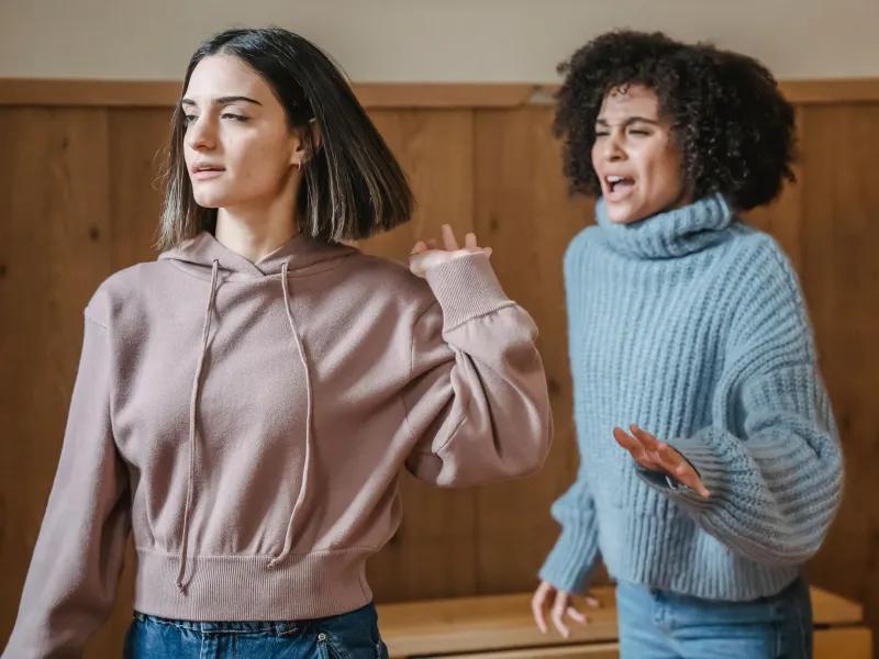 Two women acting, one walking away from the other who is shouting