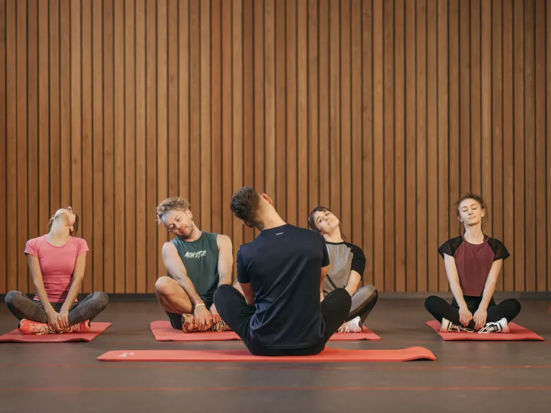 Five people sat on yoga mats on the floor stretching their necks