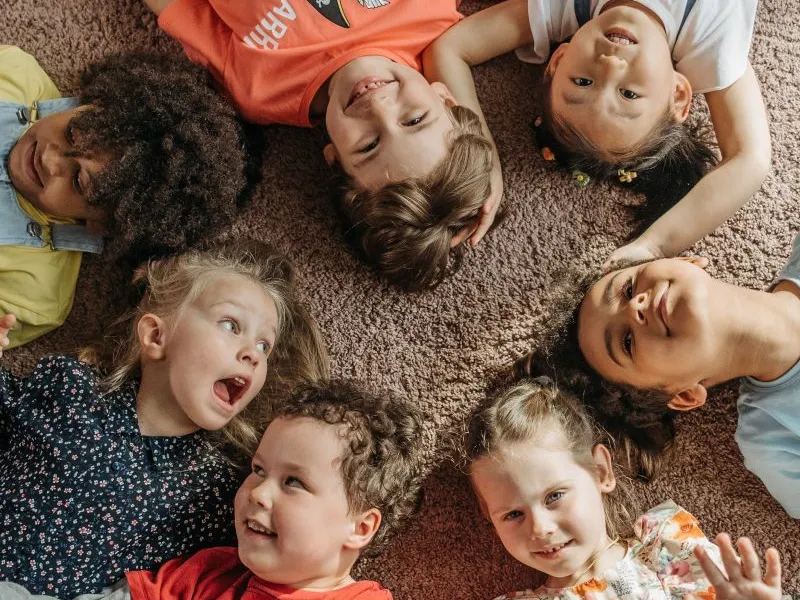 Children lying laughing in a circle.