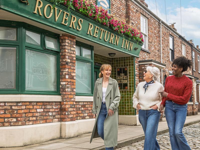 Three people walking outside the Rovers Return