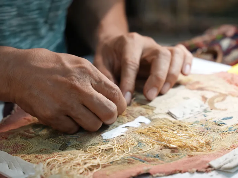 Hands of a person working on a tapestry