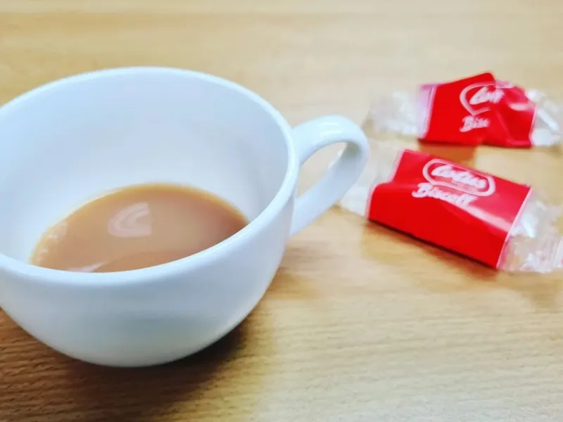 A mostly empty coffee cup and biscuits