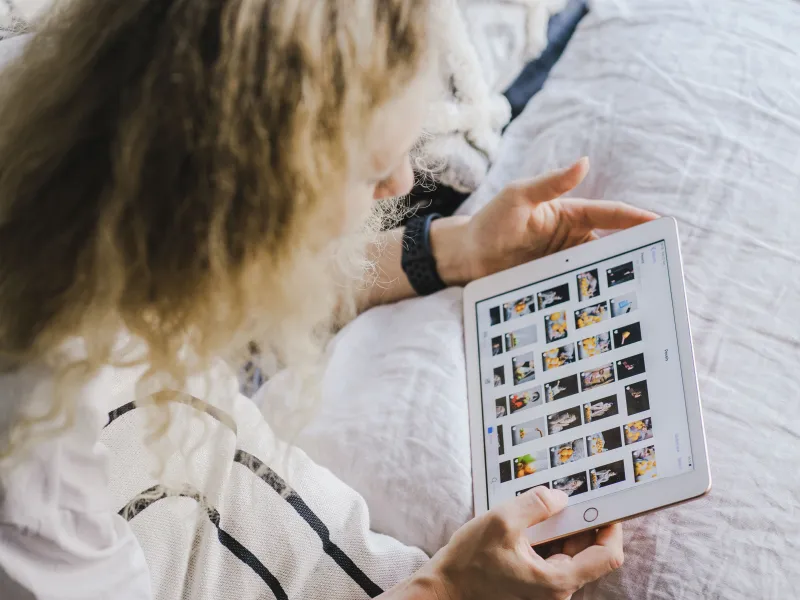 A person sitting holding a tablet, looking at content on the screen