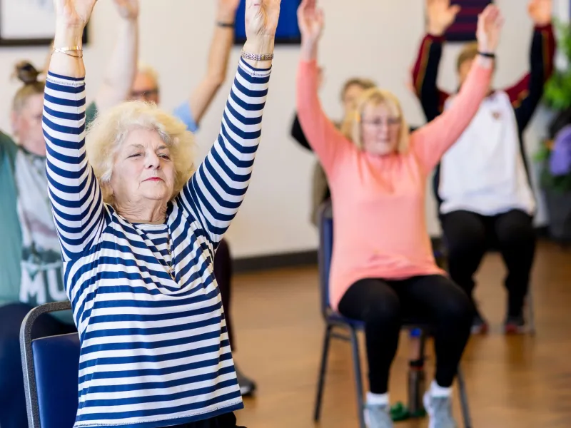 Older people doing chair yoga.