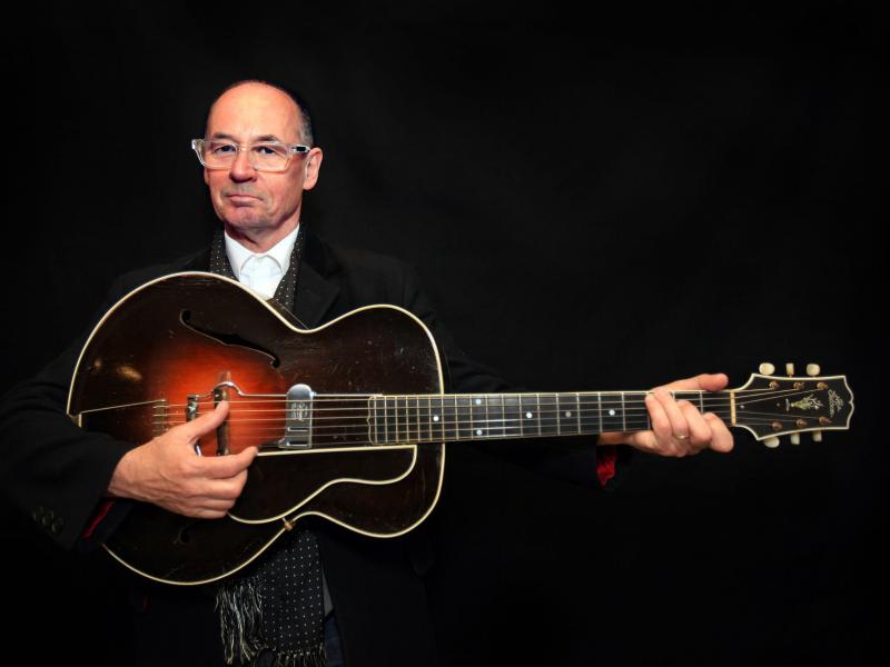 Musician Andy Fairweather Low holding a guitar