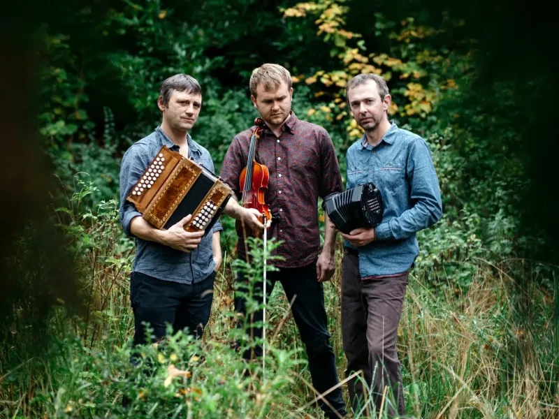 Three men holding instruments in a field