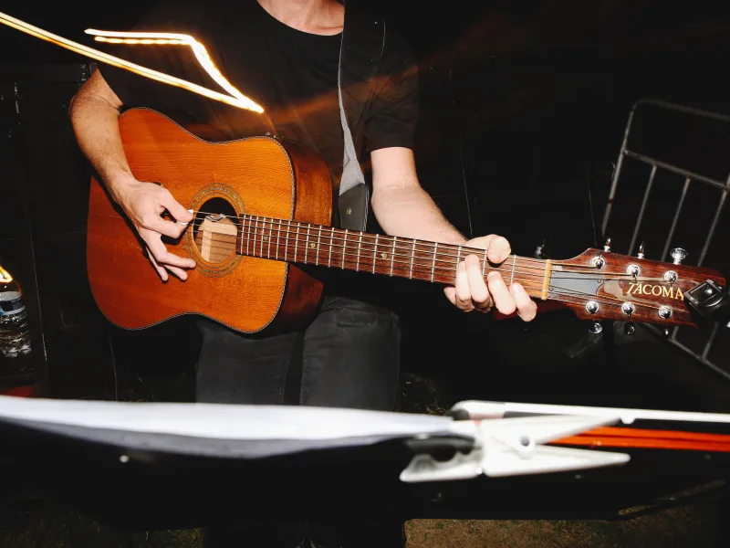Person standing and strumming a guitar