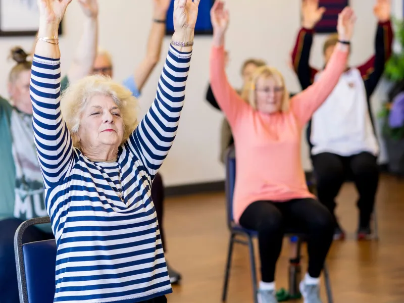 Older people doing chair yoga.