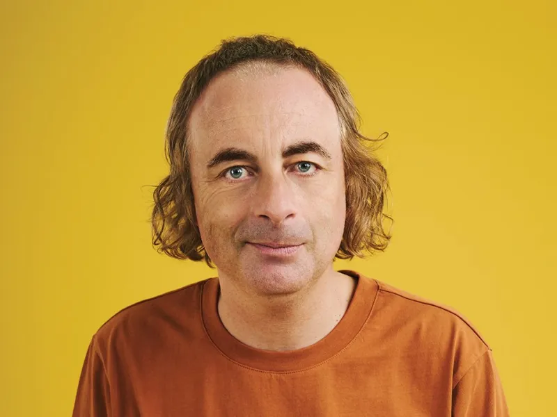 A photo of the comedian Paul Foot against a yellow background