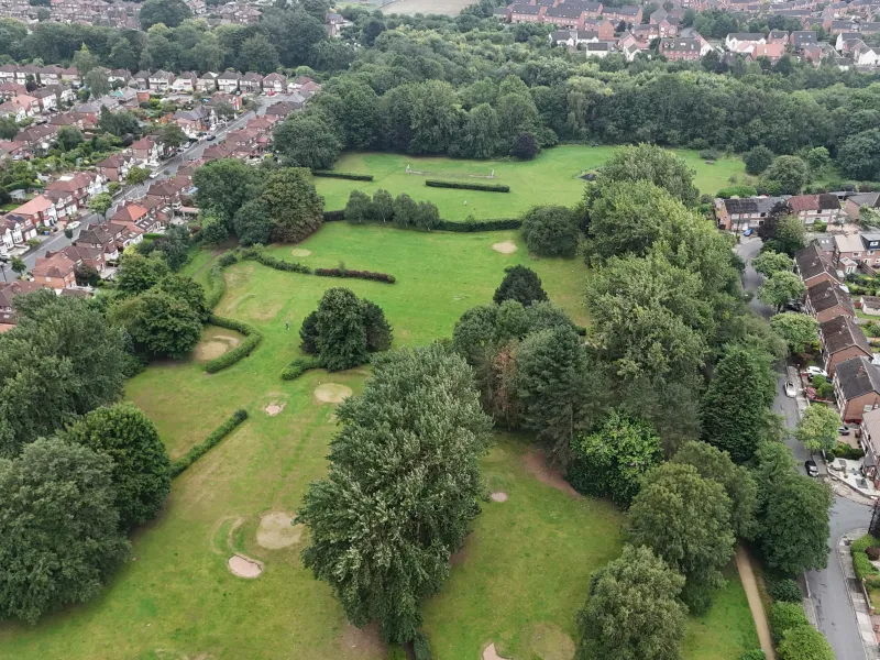An aerial photo of a park with trees and some surrounding streets 