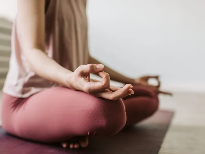 Woman sat cross-legged on the floor with hands resting on her knees