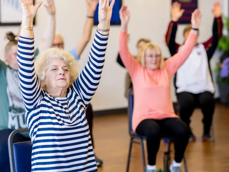 Older people doing chair yoga.