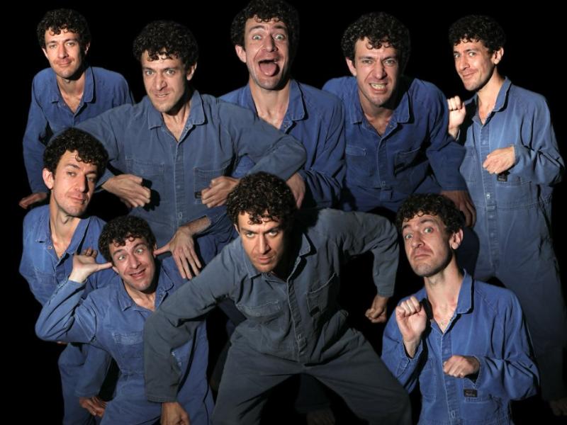 Guy Masterson performing as nine different people in a blue boilersuit