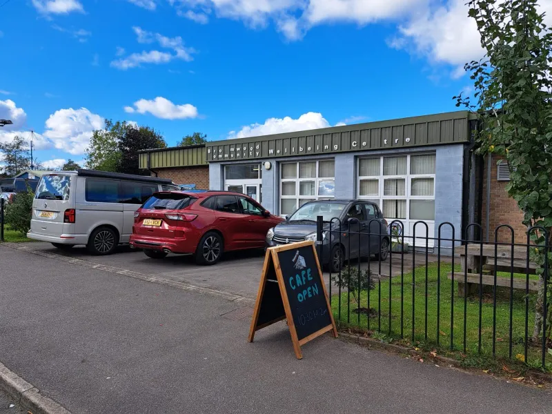 Three cars parked in front of a community building, with blue sky in the background