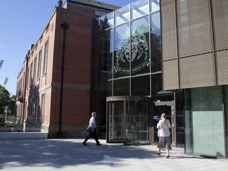 Main entrance of Town Hall and library with Council Coat of Arms etched in glass above and showing rotating glassed entrance doors and people walking towards the building.