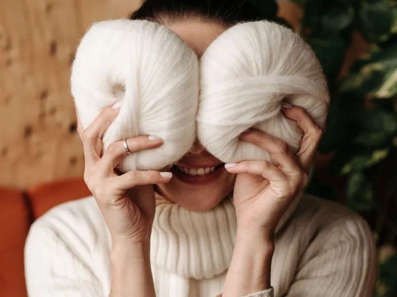 Woman hiding behind balls of yarn.