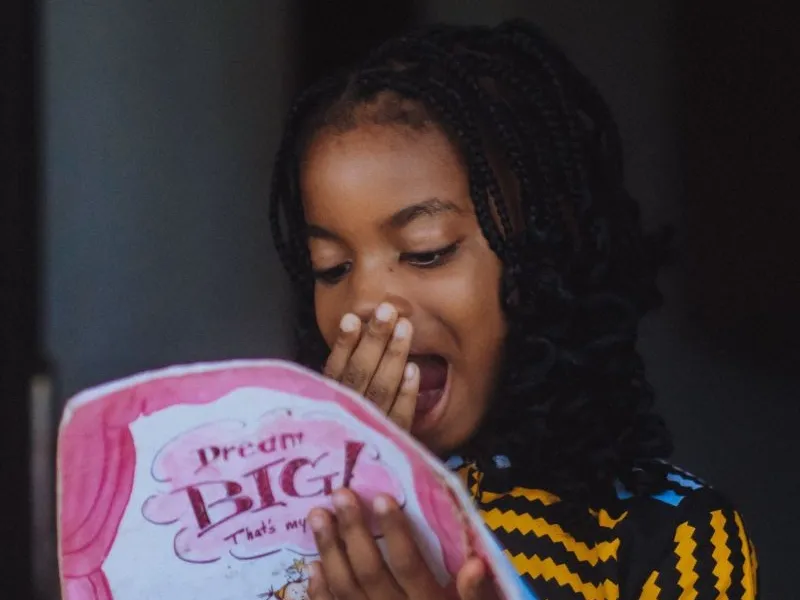 Girl looking surprised reading book.