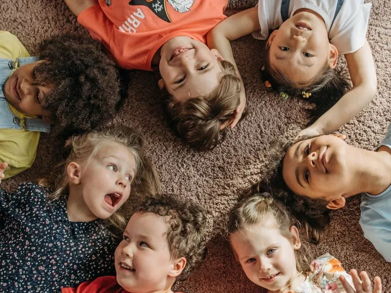 Toddlers lying laughing in circle.
