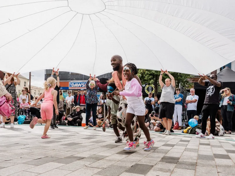 People running and playing under a giant white sheet