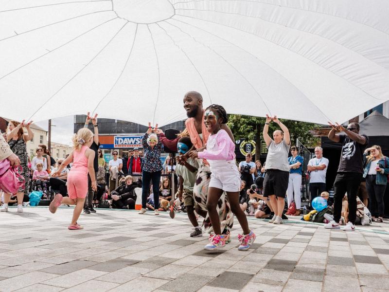People running and playing under a giant white sheet