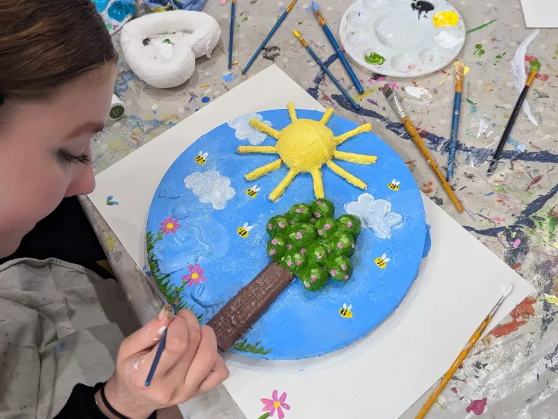 Close up of a teenager painting a relief picture on canvas 