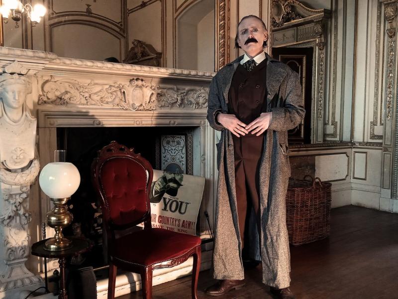 A man standing in front of a gothic fireplace