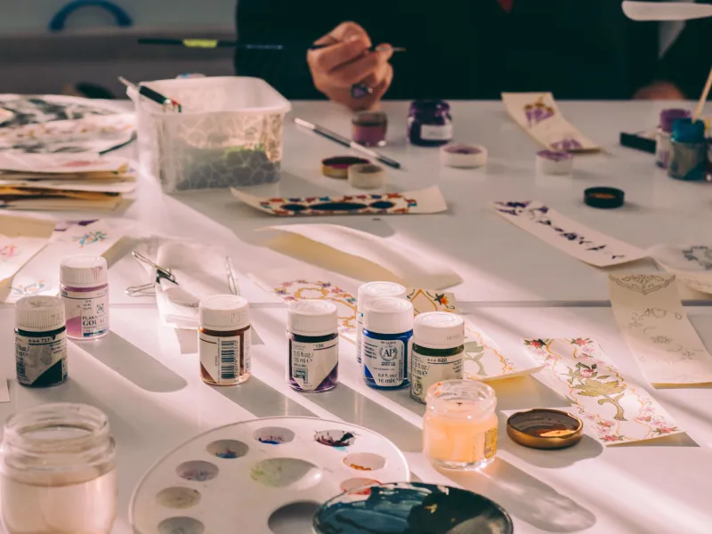 Person sitting at a table filled with crafting materials
