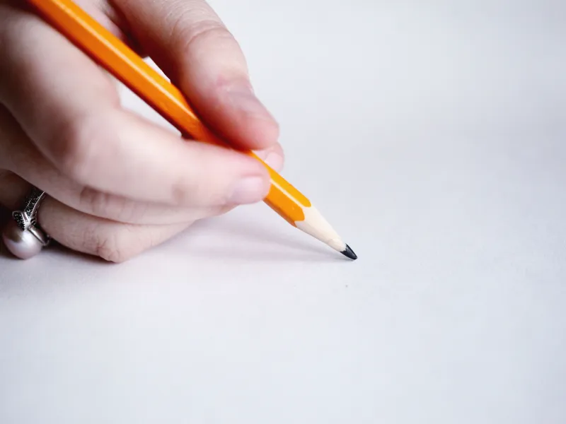 A hand holding a pencil against a white background