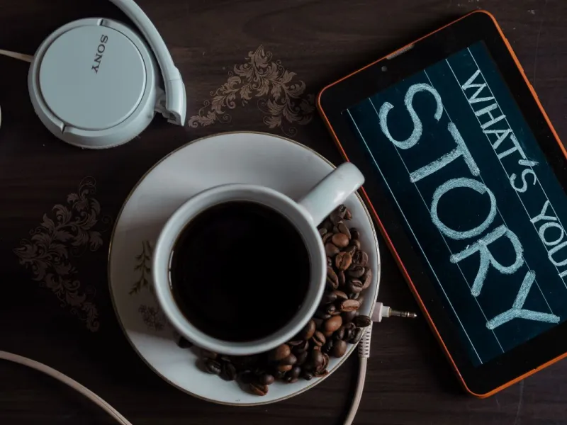 Cup of coffee and chalk board reading 'what's your story'.