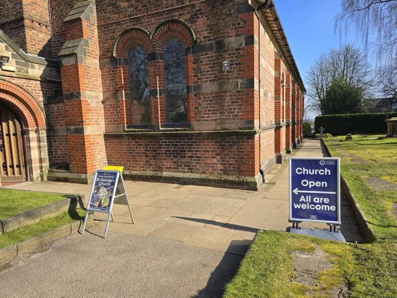 The outside of the church with a sign saying 'Church Open All are welcome'