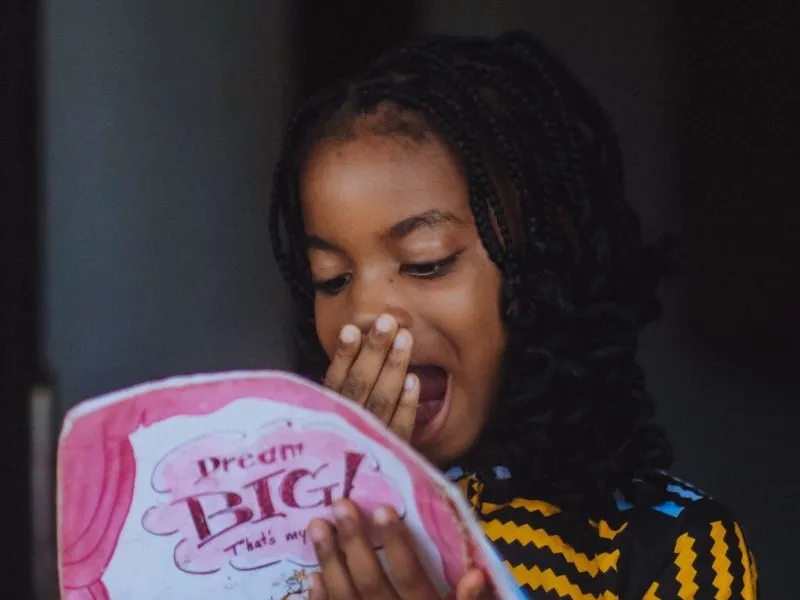 Young girl reading looking surprised.