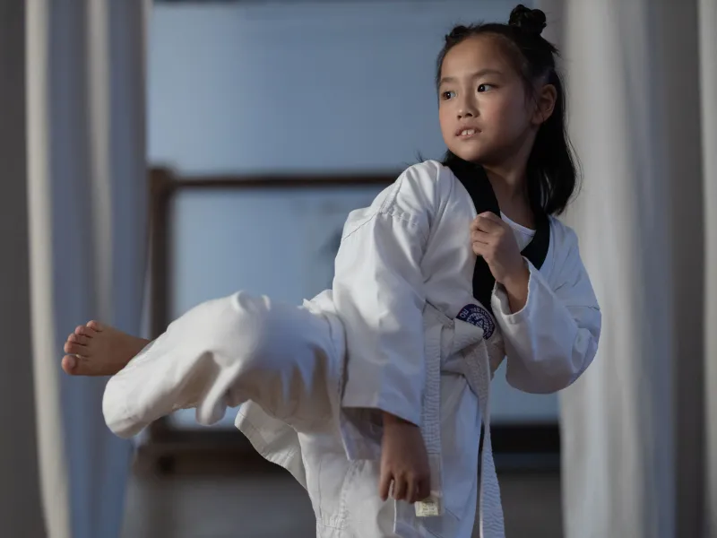 Girl in a white taekwondo suit kicking