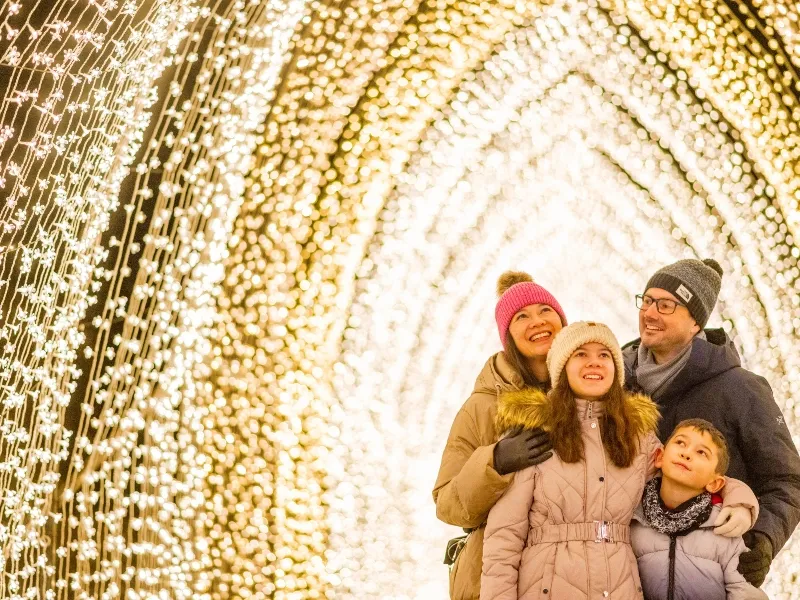 A family of four standing under a fairy lights archway