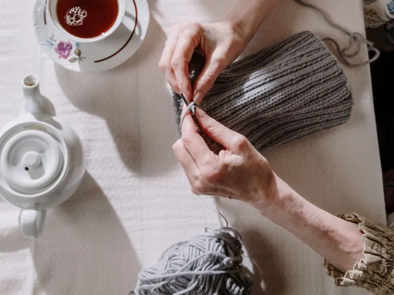 Pot of tea and hands knitting.