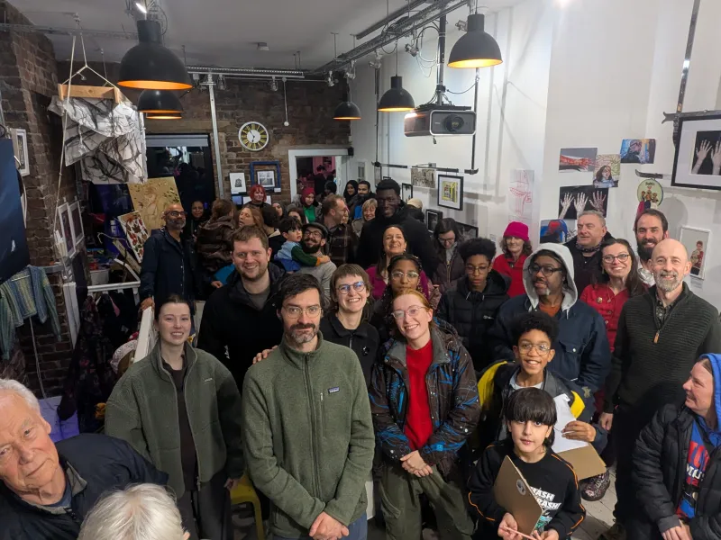 Lots of people looking at the camera and smiling in a studio space.