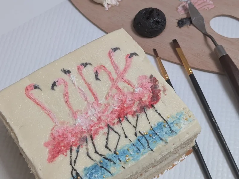 A painting of flamingos on top of a square cake