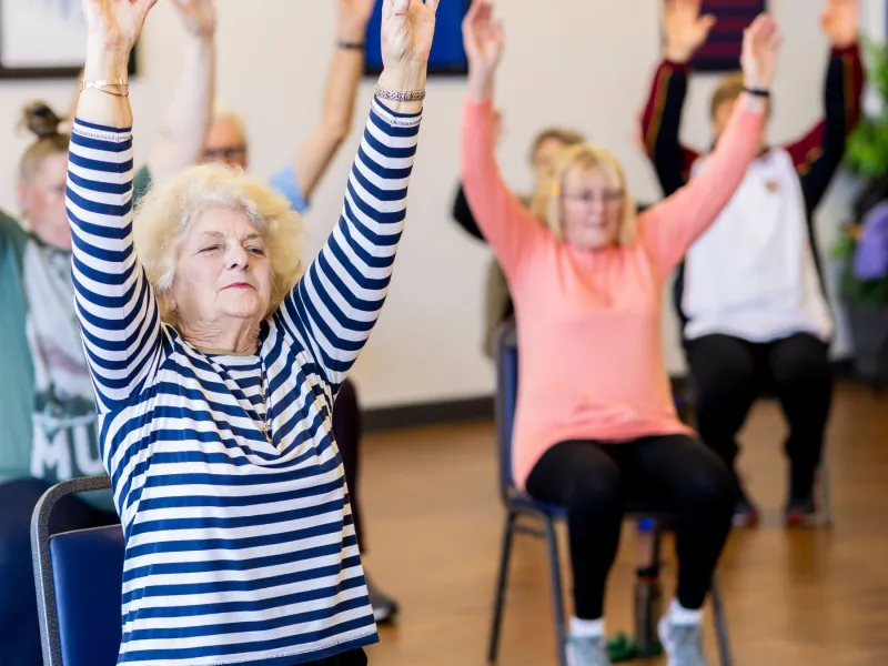 Older people doing chair yoga.